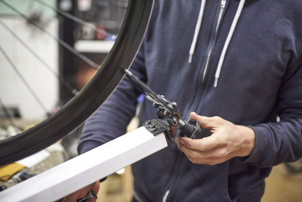 自行车维修服务:专人使用校正架对自行车车轮进行校正图片下载