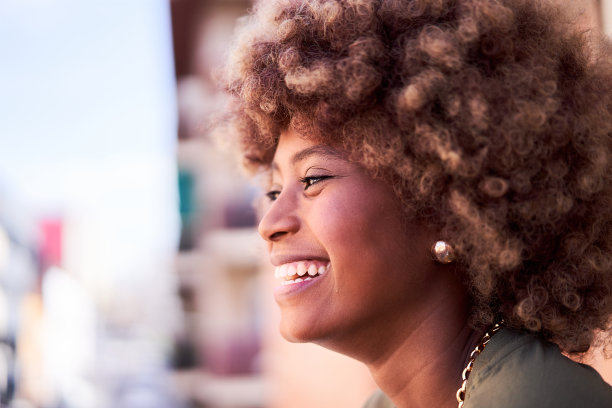 一个开朗的非洲年轻女子在户外欣赏风景的侧视图。图片下载