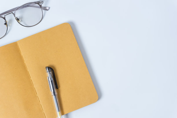 平铺办公桌照片，配上眼镜、笔和笔记本，背景为复印空间。模型图片下载