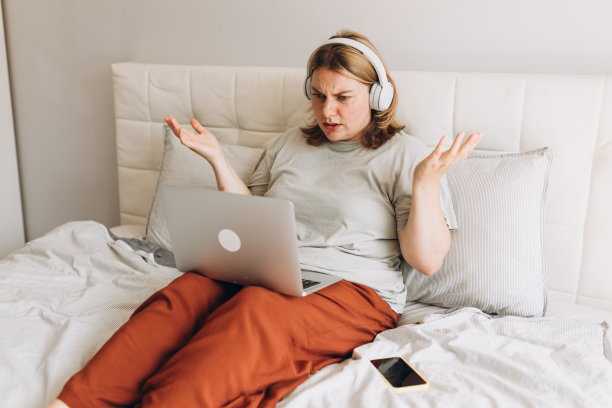 震惊的用户戴着耳机看着笔记本电脑屏幕，发现在线应用程序出现问题，连接不良，互联网服务，得到令人惊讶的坏消息。图片下载