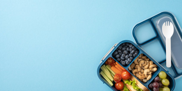新鲜营养的学校午餐盒，以各种水果、蔬菜和坚果为特色，强调健康饮食图片下载