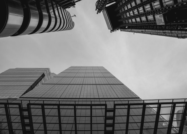 英国伦敦摩天大楼的黑白照片，低角度拍摄。天空多云，建筑又高又现代。图片下载
