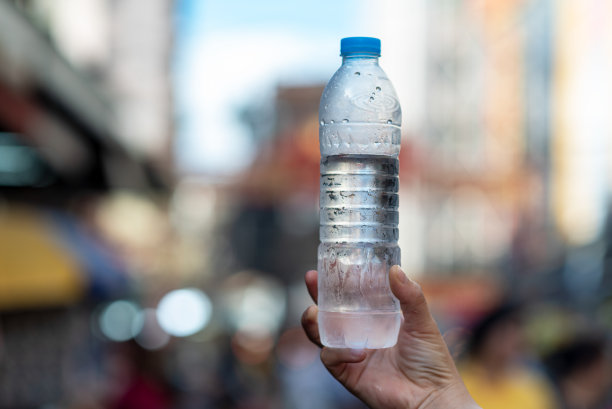 手里拿着一个塑料水瓶，模糊的背景在城市的户外图片下载