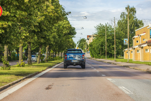 美丽的福特Ranger猛禽皮卡车的后景行驶在高速公路上的城市，被绿色的树木包围。图片下载