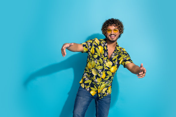 照片开朗的好心情的家伙与胡子波浪的头发穿着印花衬衫在太阳镜直接对你孤立的蓝色背景图片下载