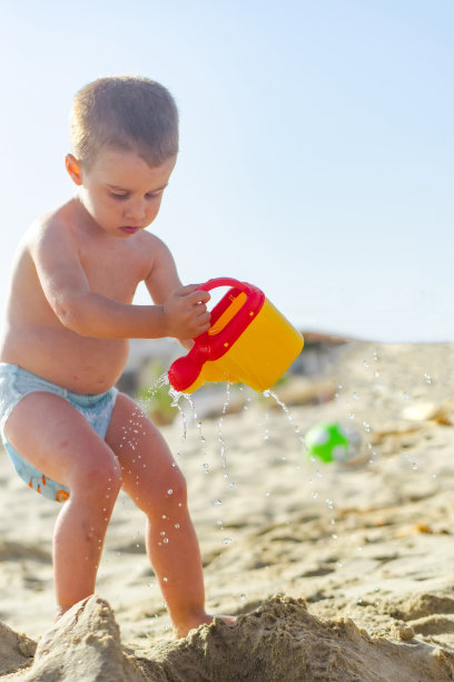 可爱的蹒跚学步的小男孩玩水的股票照片图片下载