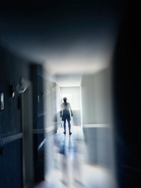 一个人走在狭窄的走廊里，看到了耀眼的灯光图片下载