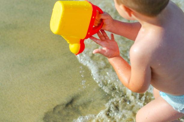 可爱的蹒跚学步的小男孩玩水的股票照片图片下载