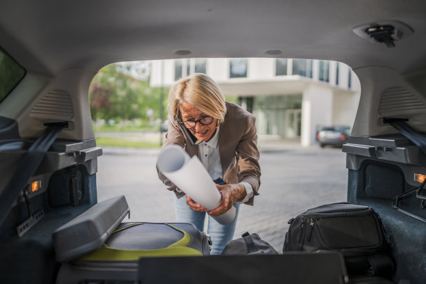 成熟的金发女子旅行时从汽车后座拿东西图片下载