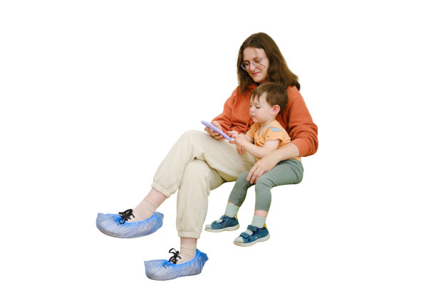 婴儿和他的母亲一起坐在医院大厅里，在医生来访前用手机玩游戏来打发时间，白色的背景是孤立的。两岁的小男孩图片下载