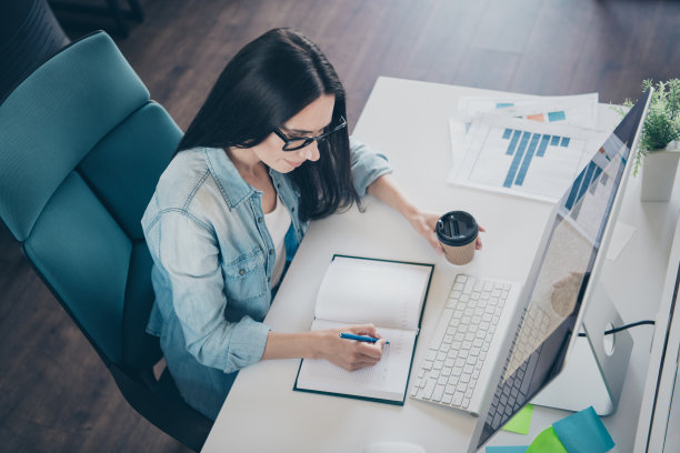 可爱的年轻女士的照片肖像做笔记喝咖啡穿着时尚的牛仔服装现代的工作场所工作办公室共同工作室内图片下载