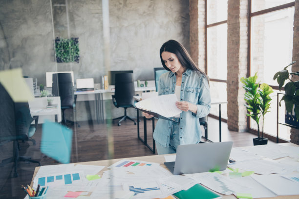 迷人的年轻女子的照片读报告文件穿着牛仔服装行政业务领导工作舒适美丽的办公室内部图片下载