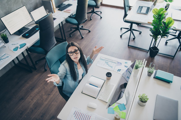 照片肖像漂亮的年轻女孩困惑耸耸肩穿着时髦的牛仔服装现代职场成功的企业主家庭办公室图片下载