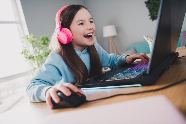 照片开朗积极的好可爱的女孩小玩家玩视频电脑游戏室在室内图片下载