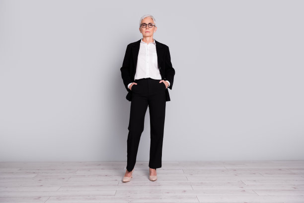 迷人的成功的高级女士穿着黑色西装的全身照片孤立的灰色背景图片下载