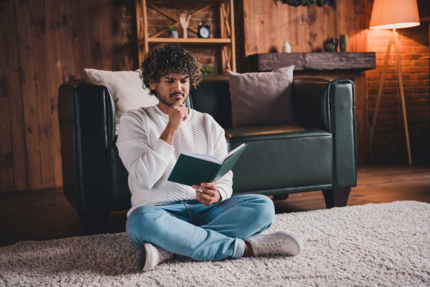 有魅力的可疑男子穿着白色运动衫在房间里看书的照片图片下载