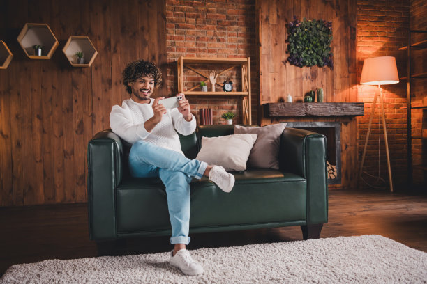 英俊的好心情的家伙穿着白色运动衫玩游戏现代设备在室内房间家里房子的照片图片下载