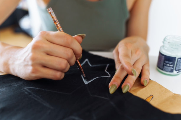 年轻女子用颜料在衣服上画画，这是手工制作的作品。定制图片下载