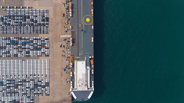 无人机拍摄的大型汽车运输船在拖船引导下停靠到地中海港口的照片图片下载