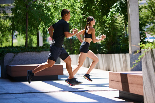 两名运动员的动态照片，男人和女人，并排跑在阳光明媚的公园。早晨例行公事。图片下载