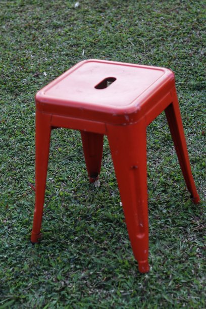 红色的金属吧台凳。椅子在绿草地上。图片下载
