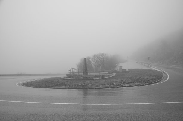 弯曲的道路。雾蒙蒙的路上，黑白照片。清晨，雾蒙蒙的公路上。图片下载