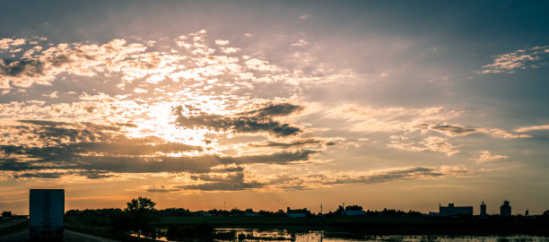 美国公路上的卡车和汽车在云层后面的彩色太阳全景照片图片下载