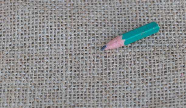 简约的背景与粗麻布织物上的铅笔，复制空间的概念。绿色蜡笔在粗糙的布料纹理上的俯视图照片图片下载