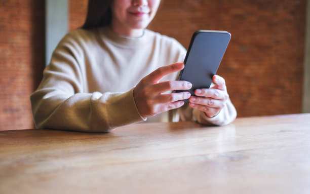 一个女人手持并使用手机的特写图片图片下载