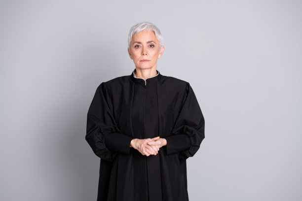 照片中，睿智的法官女士穿着黑色长袍，穿着灰色背景，看起来很严肃图片下载