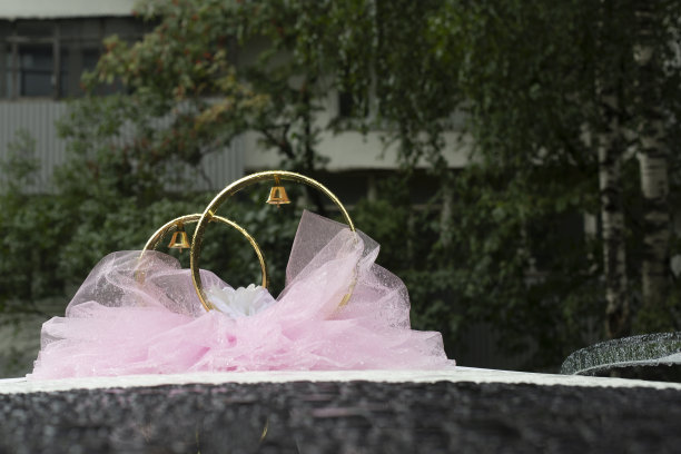 婚车装饰。车辆顶部的环。粉色缎带在机器上。图片下载