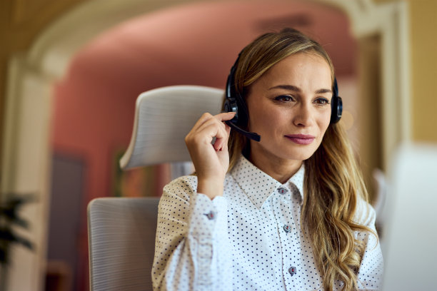 一名女接线员用耳机和麦克风与人交谈的特写照片。图片下载