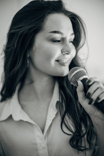黑白照片里的女人对着麦克风唱歌。图片下载