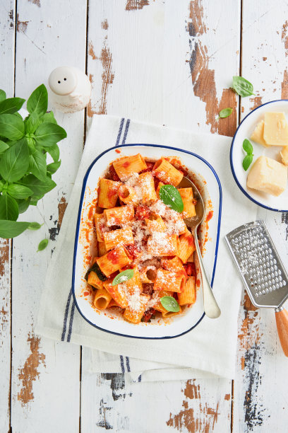 意大利通心粉配帕尔马干酪，番茄帕萨塔酱和罗勒在复古的盘子里，旧的木制红色质朴的桌子背景。传统意大利面食食谱。封面或文章前视图。图片下载