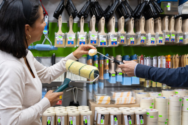 一位妇女在油漆店被建议选择工具来粉刷和装饰她的房子图片下载