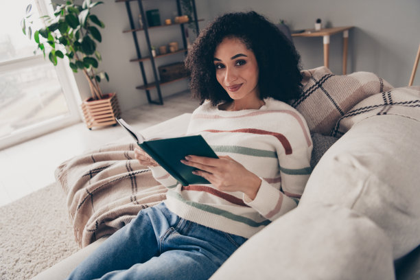 照片肖像迷人的年轻女子坐沙发书有趣的故事穿着休闲的衣服舒适的白天光家室内客厅图片下载