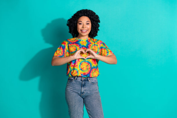 照片可爱可爱的好女人穿着时尚的印花衣服手臂心脏标志孤立在青色背景图片下载