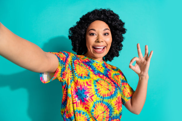 照片可爱的积极高兴的女人穿着时尚的印刷ok标志衣服孤立的青色背景图片下载