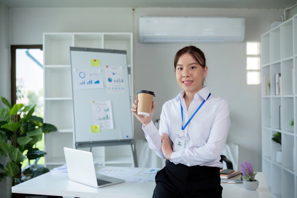 在现代办公环境中，年轻的女商人在办公桌前用笔记本电脑和咖啡工作图片下载