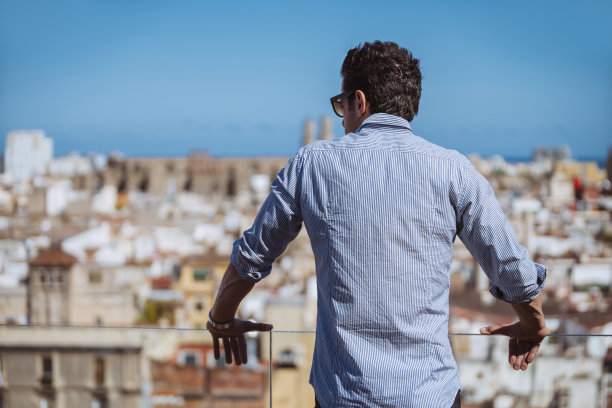 商人从阳台望向远处的城市天际线图片下载