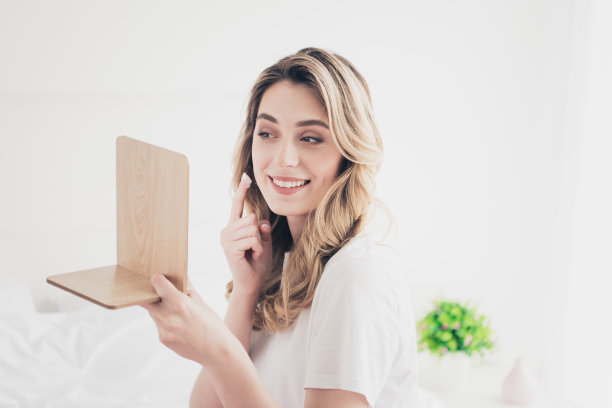 积极的女孩在日光房间里用面霜洁面照镜子的照片图片下载