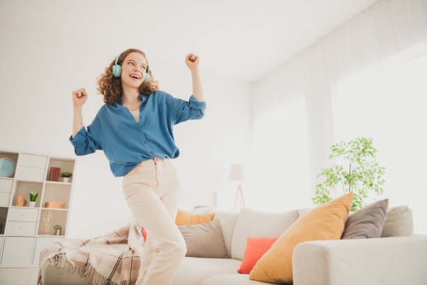 照片快乐的年轻女孩耳机跳舞的蓝色衬衫享受生活的新公寓房间，光的房子，平的室内图片下载