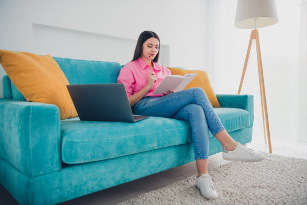 闪亮可爱的女孩穿着粉红色的衬衫，休息，沙发，写书，现代小玩意在室内的房子，公寓房间的照片图片下载