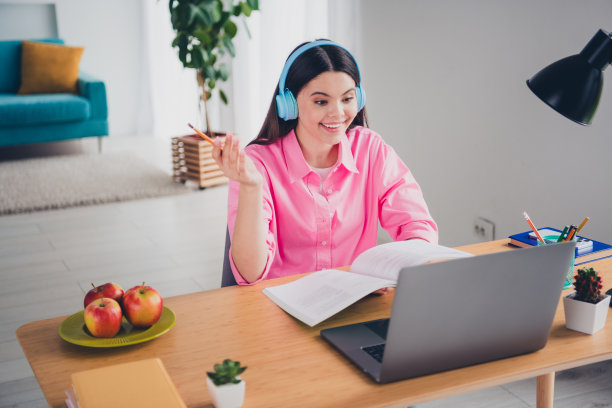 兴奋开朗的女士照片穿着粉红色的衬衫，耳机远程教育现代小工具在室内房间家里的房子图片下载