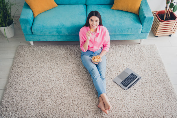 漂亮的开朗的女士穿着粉红色的衬衫享受饼干聊天现代设备在室内房间的房子的俯视图照片图片下载