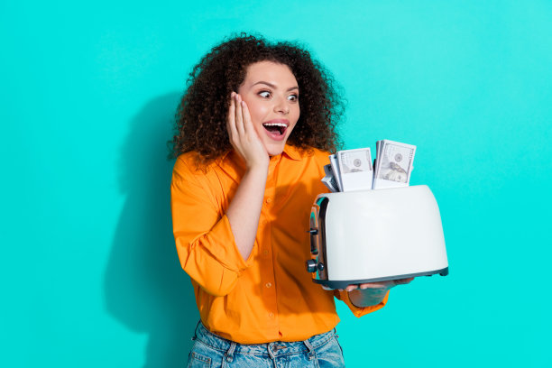 欣喜若狂的印象女人的照片，波浪发型，穿着衬衫，看着烤面包机，在绿松石色的背景上孤立的钱图片下载