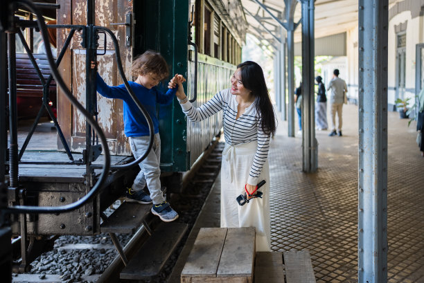 年轻的亚洲妇女在帮助她的儿子上火车图片下载