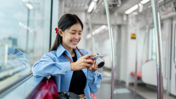一位乐观的亚洲女性旅行者在乘坐空中列车上下班时正在查看相机上的照片。图片下载