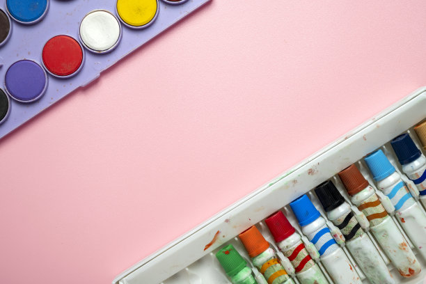 粉红色的背景上放着一盒蜡笔和一套水彩画图片下载