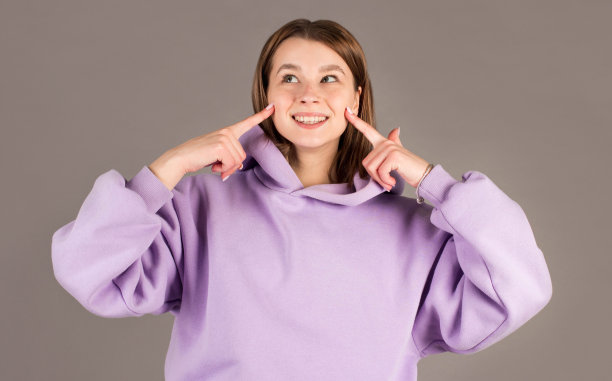 特写照片，美丽的黑发女孩用手指触摸她的脸颊，看着相机，孤立的灰色背景图片下载